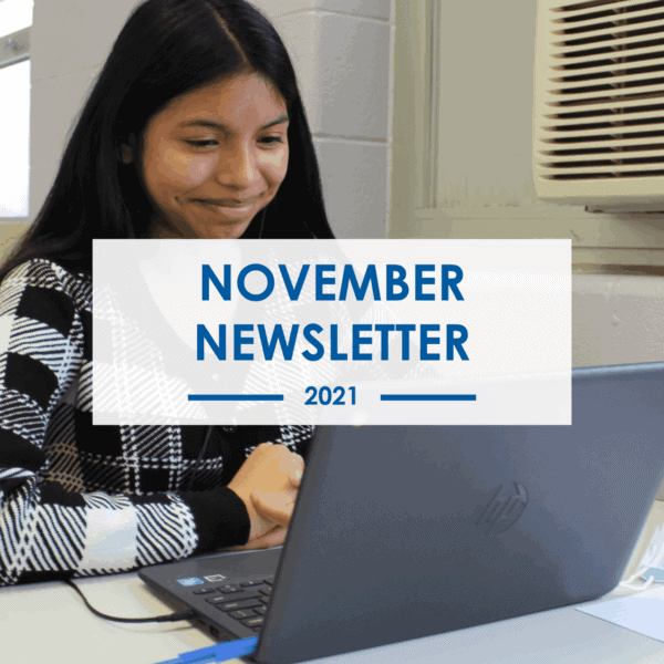 A young woman sits at a desk smiling and looking at a laptop. Over the image, a white box with blue text reads November Newsletter 2021. An air conditioner is visible on the wall behind her.