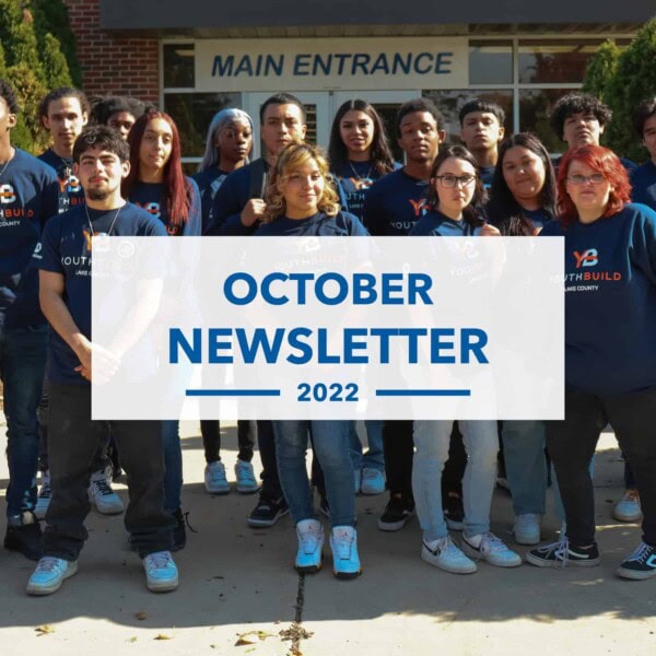 A diverse group of young adults wearing matching blue shirts stands in front of a building labeled Main Entrance. Overlaid text reads: October Newsletter 2022.