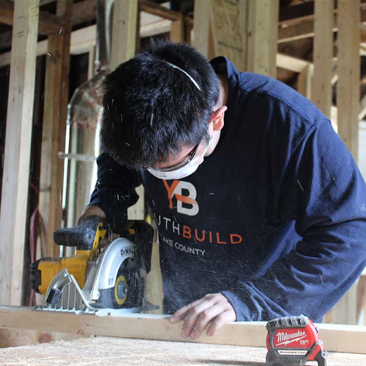 YouthBuild member Edward cutting wood on site at the Seymour project