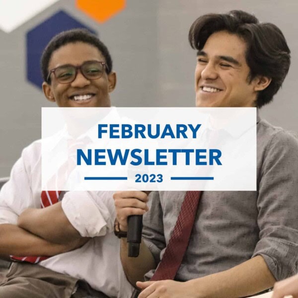 Two young men, dressed in shirts and ties, smile while sitting together. One holds a microphone. A white banner reading February Newsletter 2023 covers the center of the image.