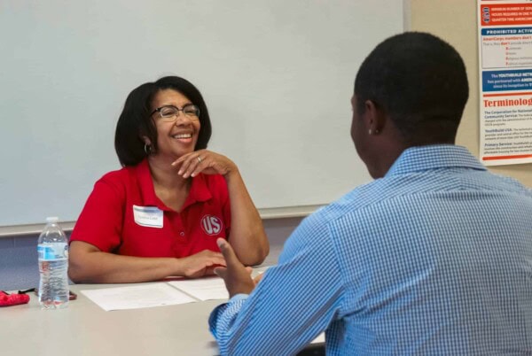 A woman in a red shirt sitting at a table with a man in a blue shirt.